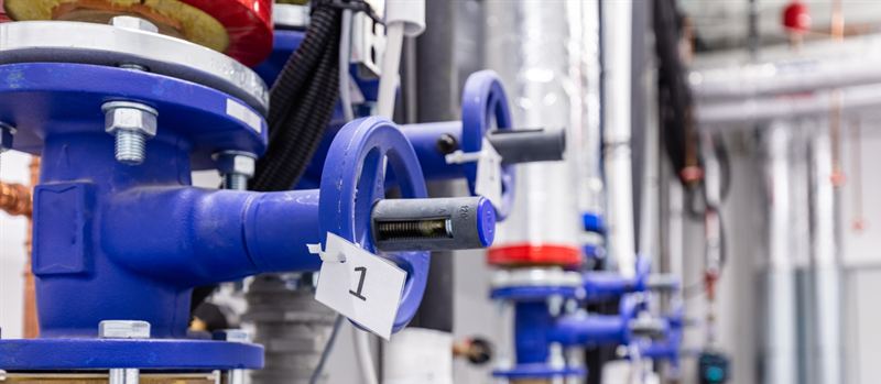 Blue flanged valves and insulated pipework in a commercial plant room