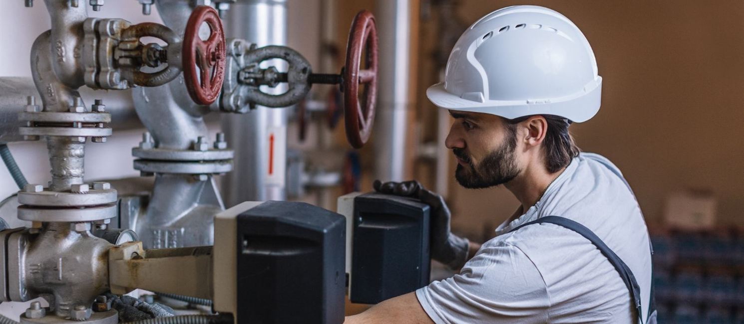 Commercial gas engineer checking plant room valves and gauges in Glasgow