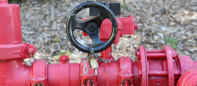 Red industrial gas pipeline with a locked valve at a site in Blackfield | Gas Main Installation Red industrial gas pipeline with a locked valve at a site in Blackfield